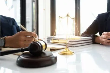 A lawyer and a client meeting next to a gavel and scales of justice